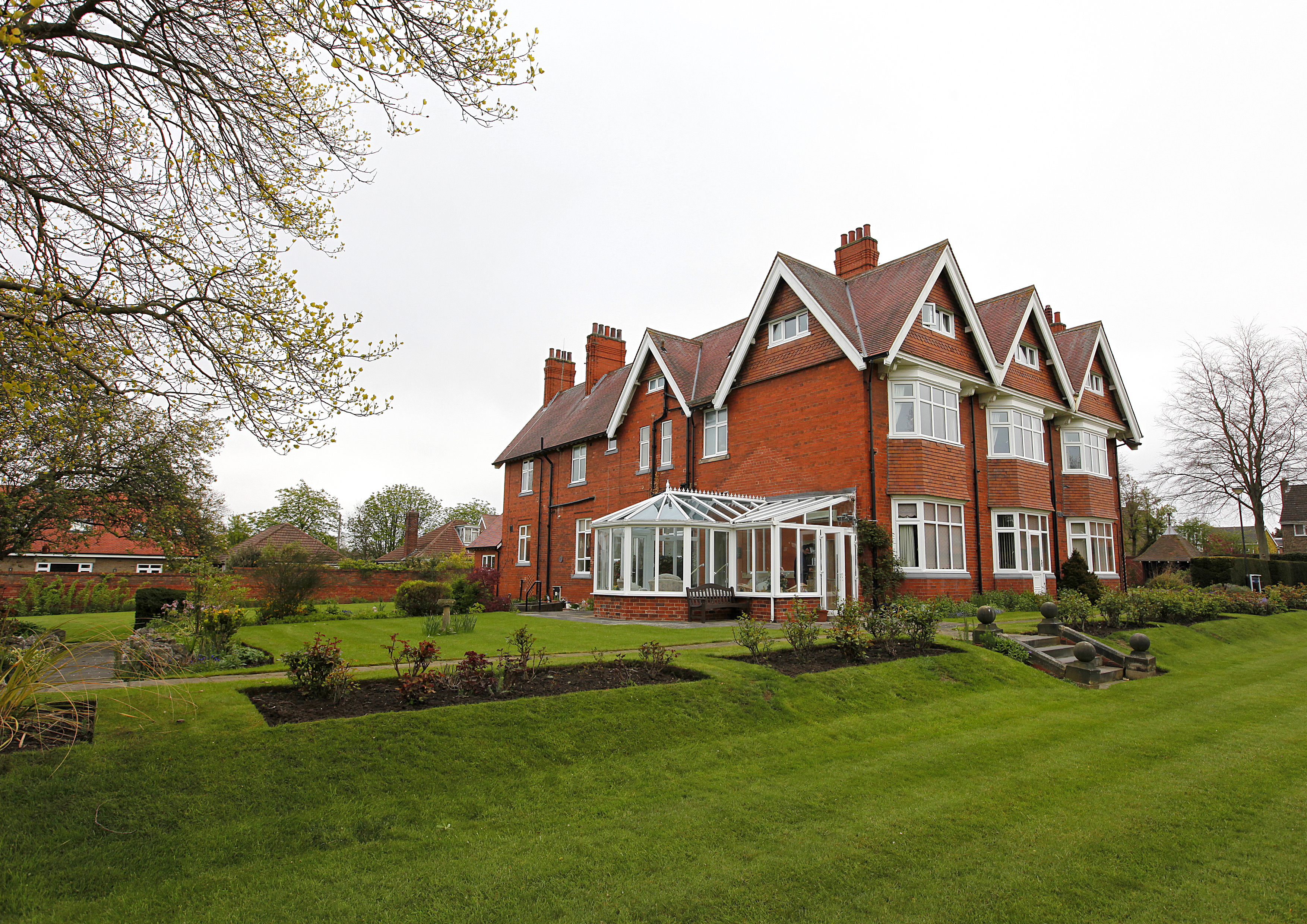 Large red bricked house with a conservatory and large garden