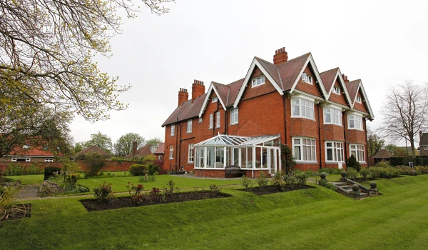 Large red bricked house with a conservatory and large garden