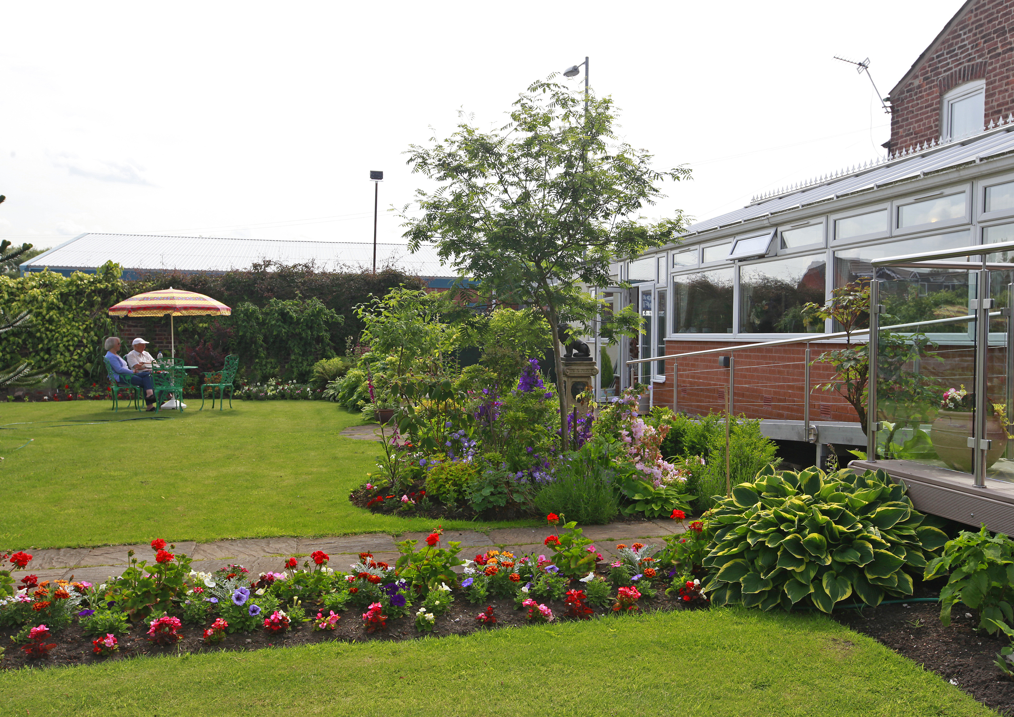 Garden borders full of colourful flowers and residents sat at a table in the distance
