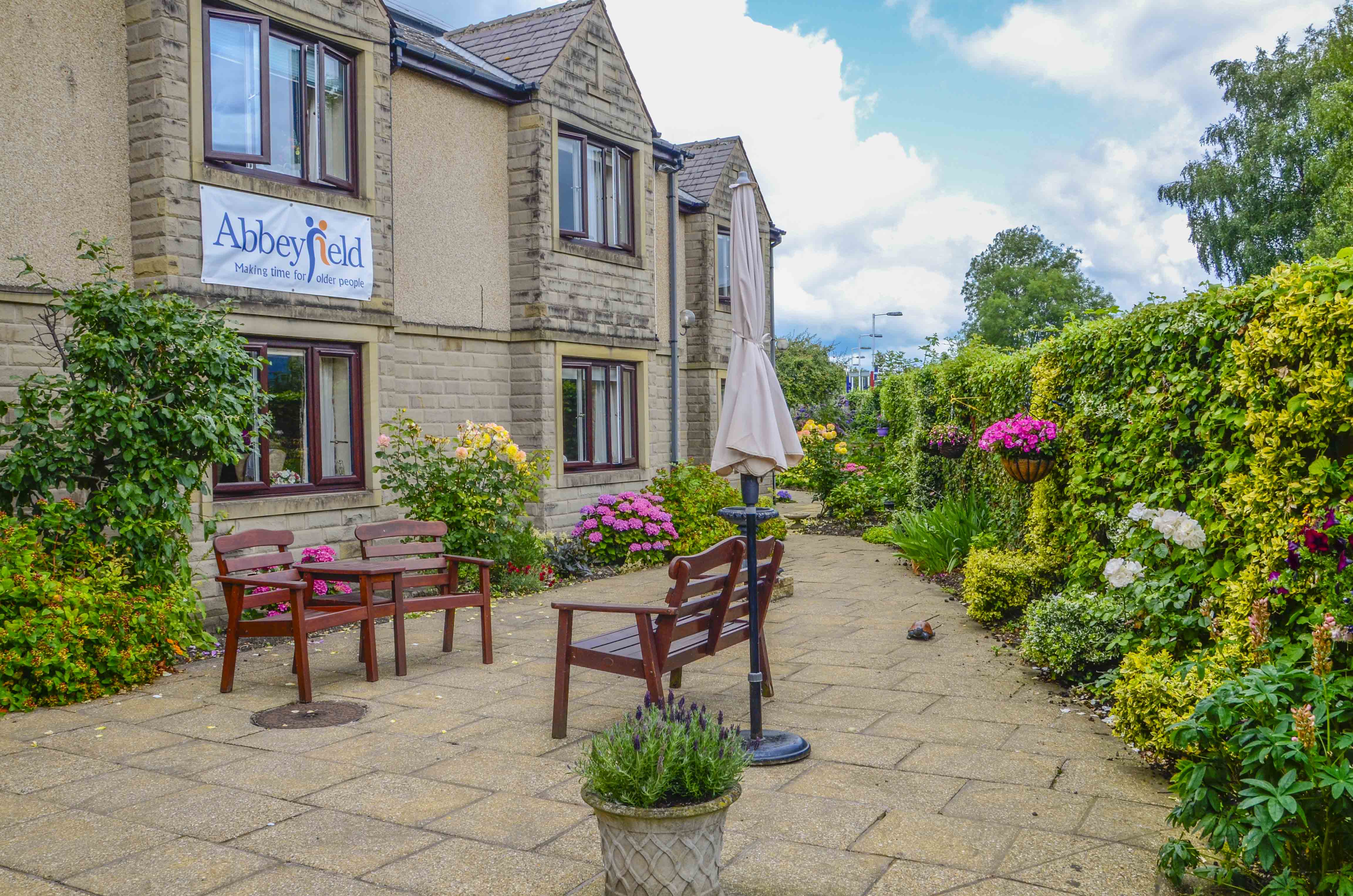 Beautiful bright garden with pink flowers and bench at Castle View House, BB7 2DT