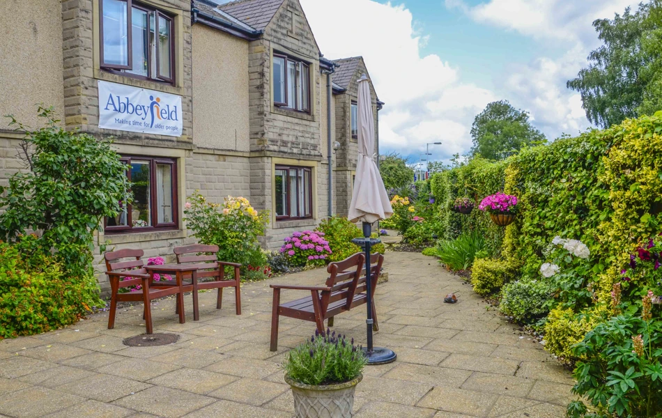 Beautiful bright garden with pink flowers and bench at Castle View House, BB7 2DT