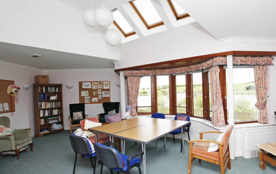 Large activity room with tables and chairs at Staveley House