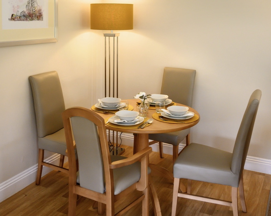Dining table set for dinner with a tall lamp lit in the background