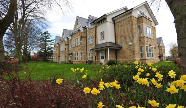 Abbeyfield The Beeches a large stone building set behind a bed of daffodils