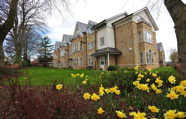 Abbeyfield The Beeches a large stone building set behind a bed of daffodils