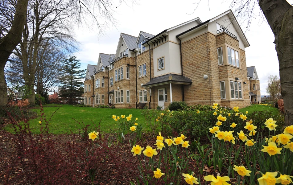Abbeyfield The Beeches a large stone building set behind a bed of daffodils