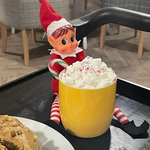 Elf on the shelf toy with a hot chocolate with lots of cream
