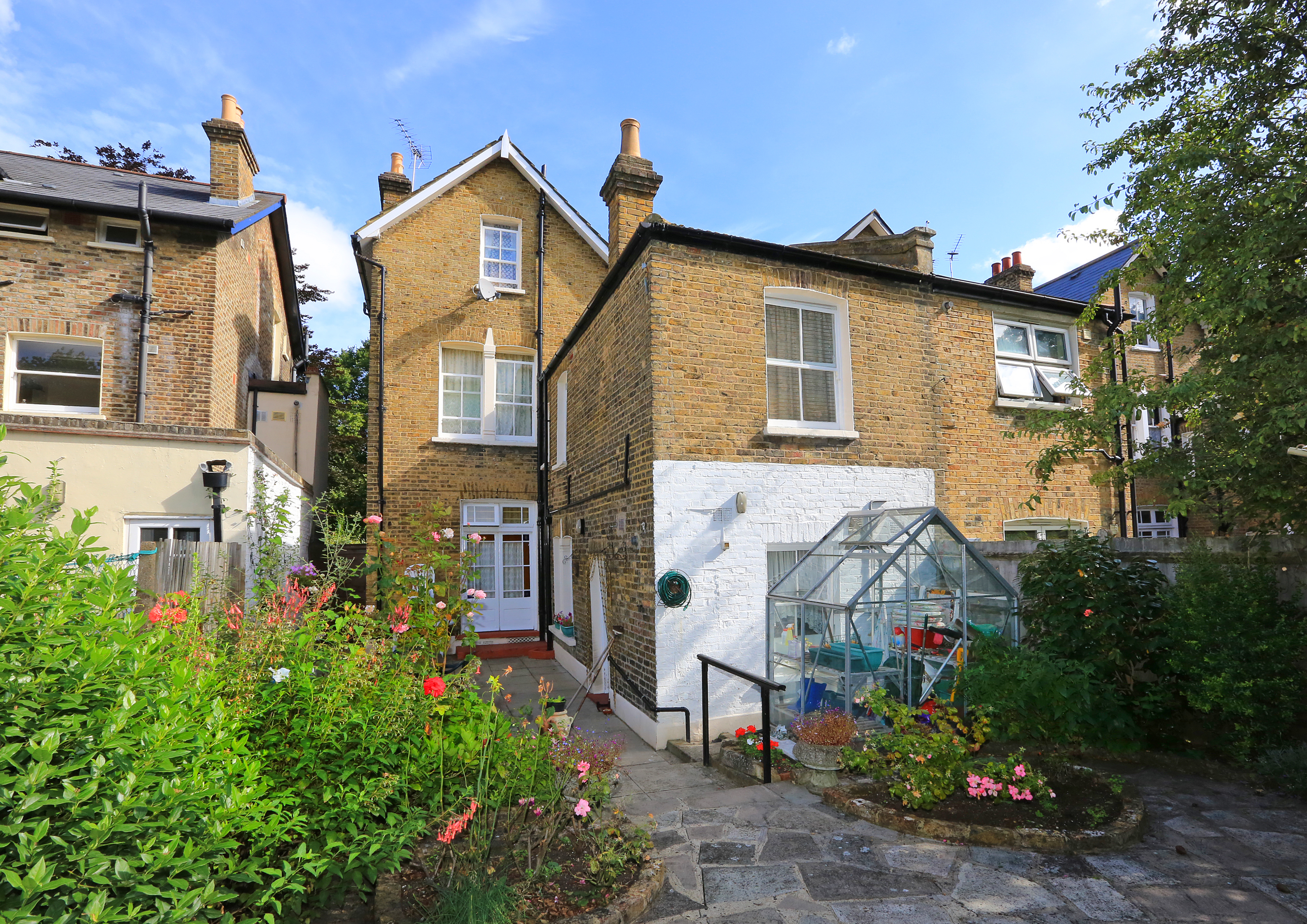 Paved back garden at the Walter Large House with greenhouse for residents to use