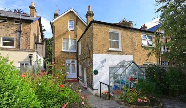 Paved back garden at the Walter Large House with greenhouse for residents to use