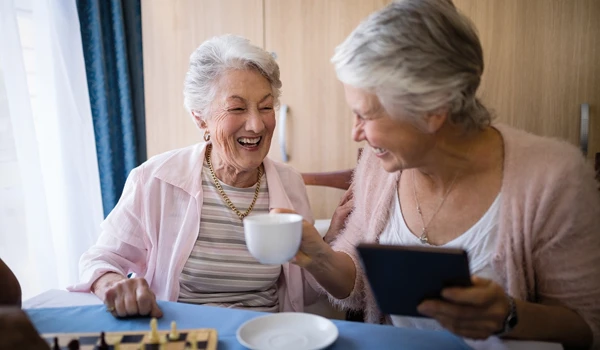 Two Smiling Older Women Enjoying A Game Of Chess And A Tea