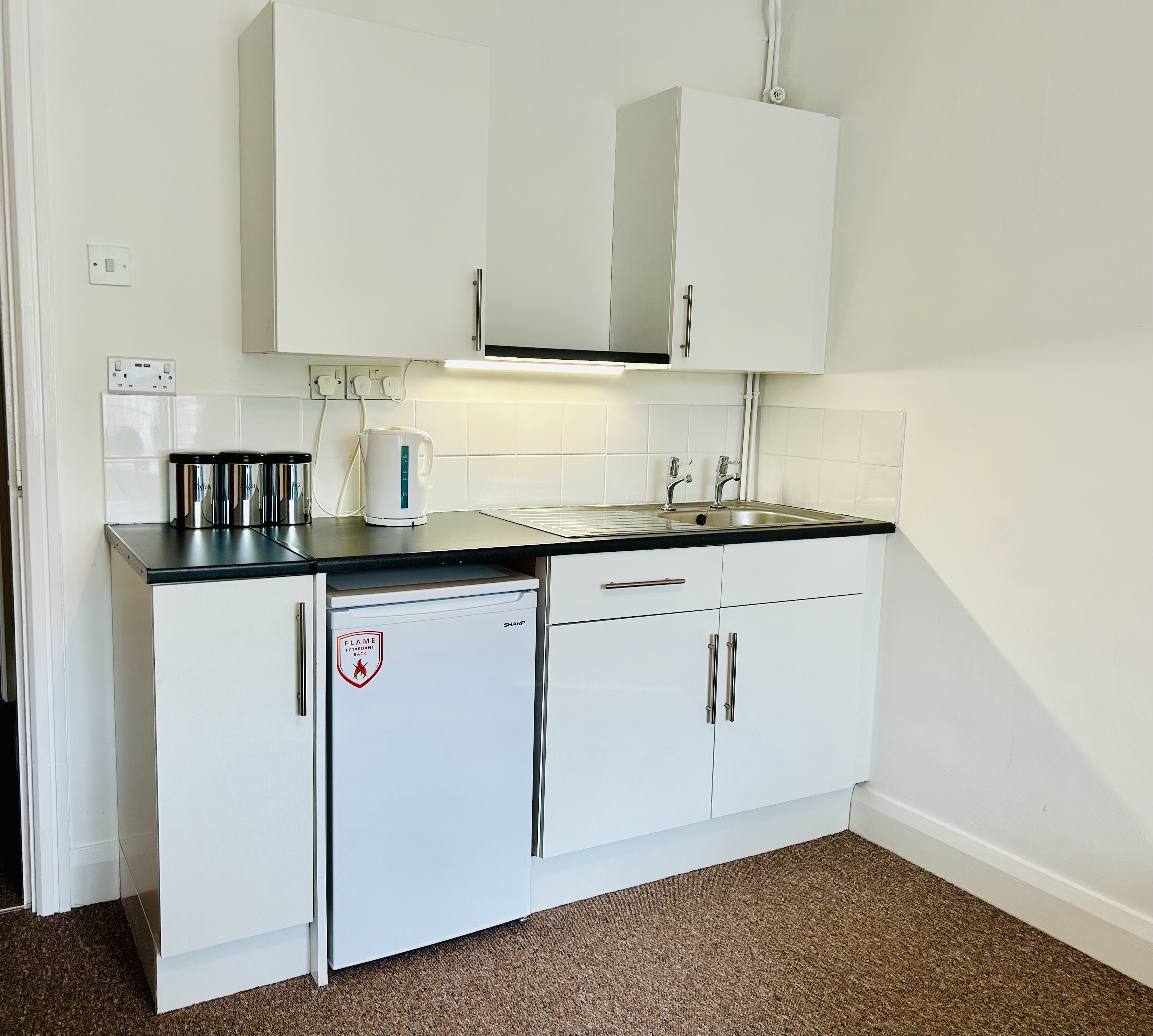 A kitchenette in one of our rooms with a fridge, sink and cupboard space
