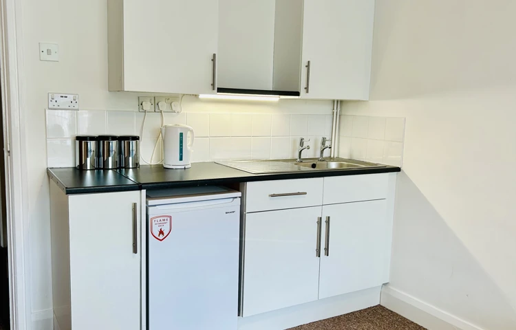 A kitchenette in one of our rooms with a fridge, sink and cupboard space