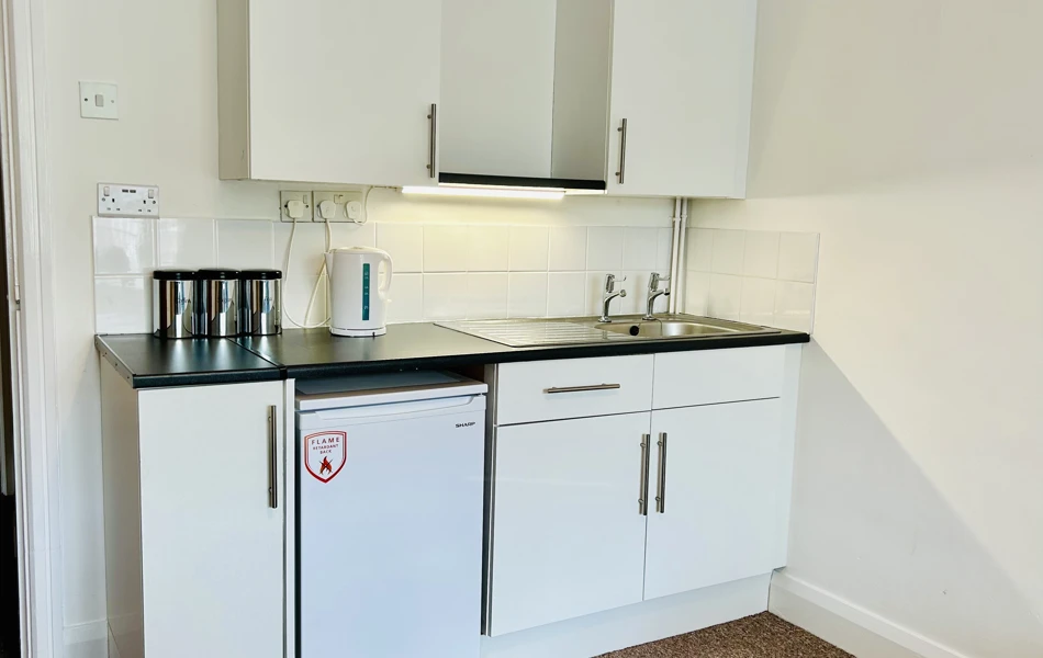 A kitchenette in one of our rooms with a fridge, sink and cupboard space