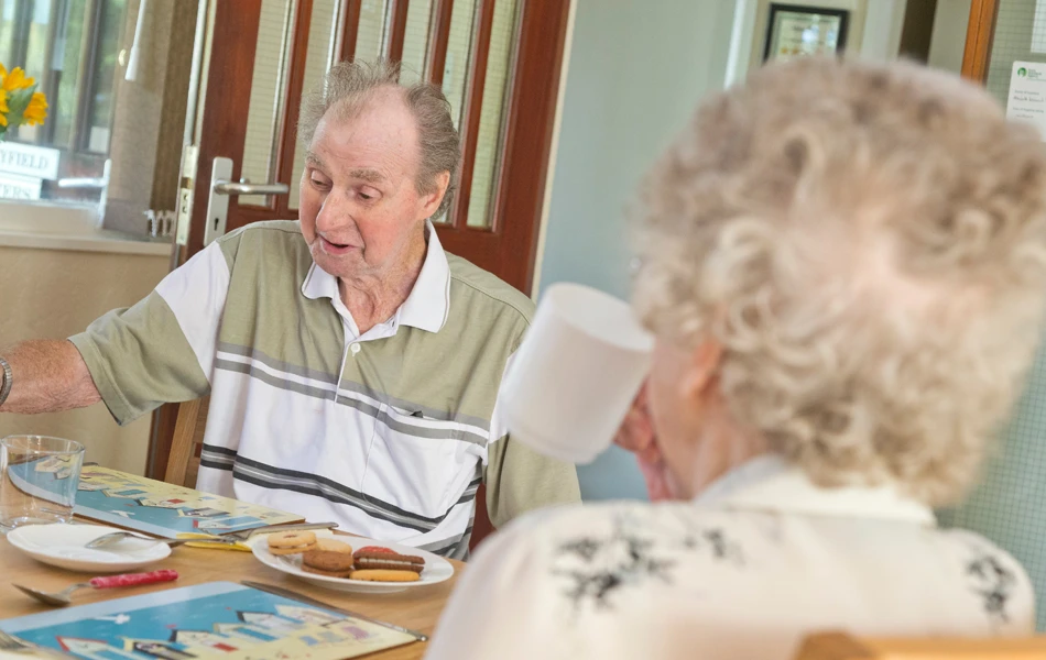 Residents are sat at the table enjoying tea and biscuits