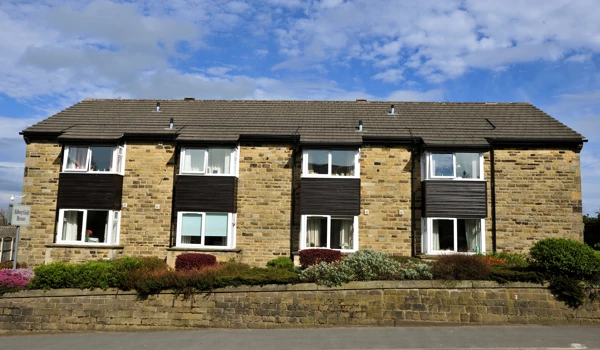 Full view of the front of the house with a stone wall around the garden