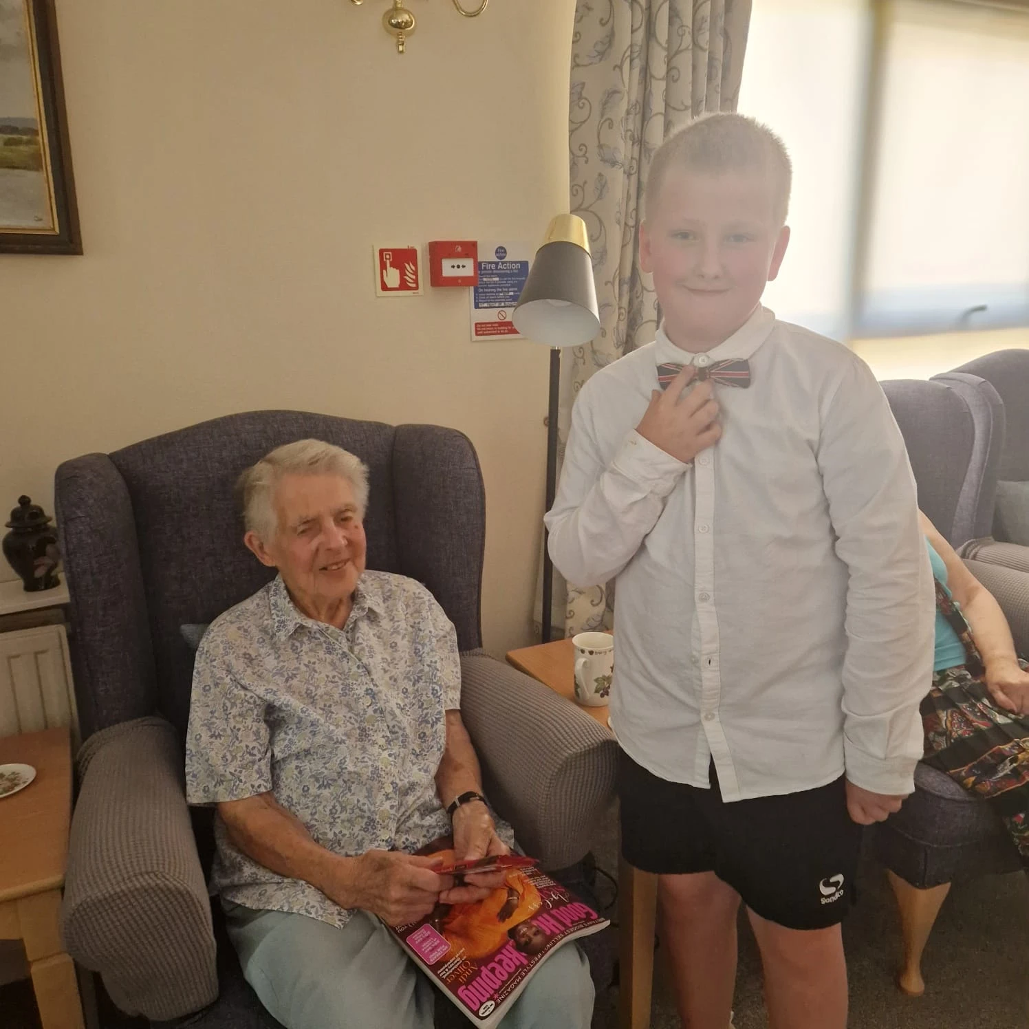 Local child standing next to one of the residents sitting down in their armchair