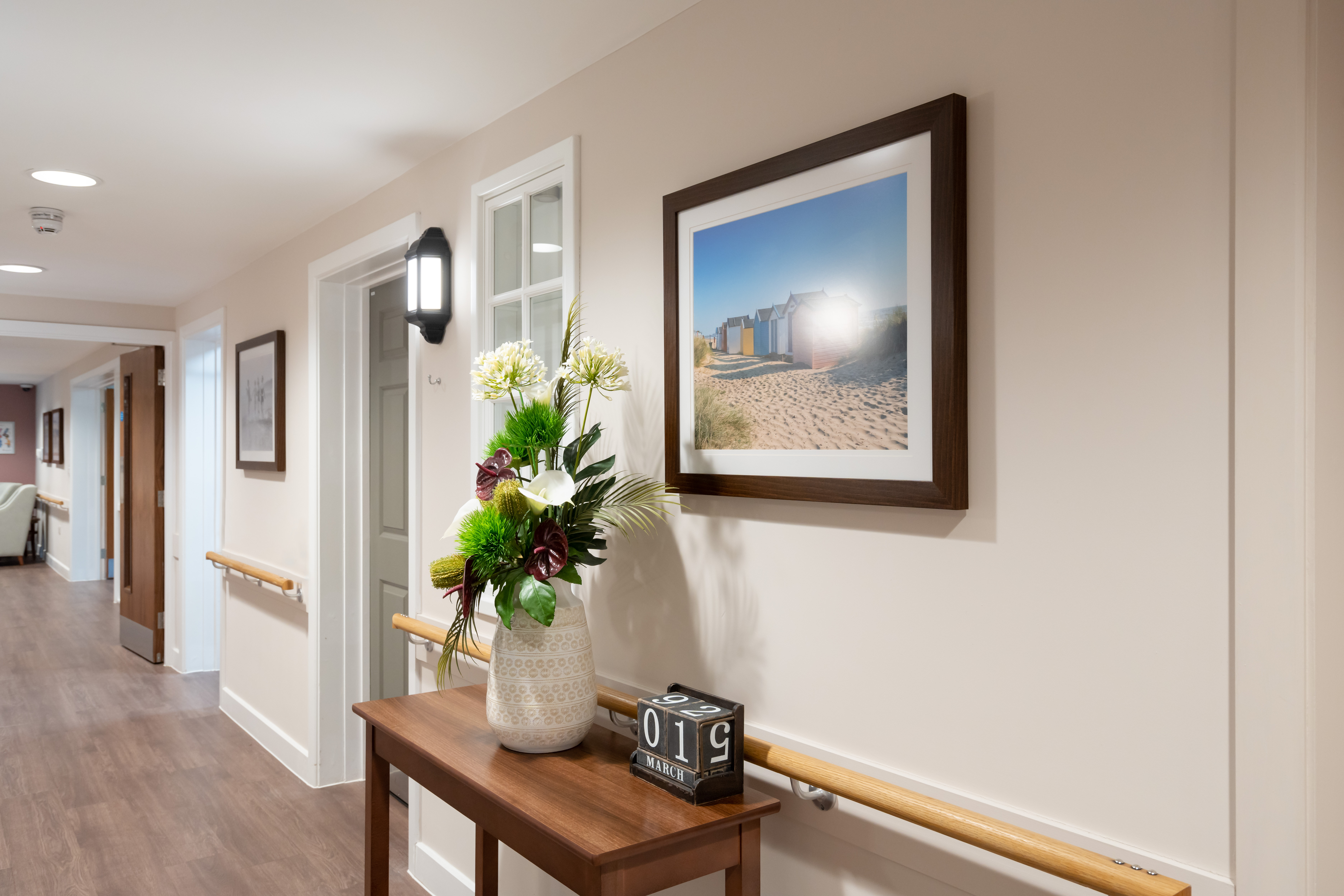 Bright hallway at Westall House with artwork, floral arrangement and handrails
