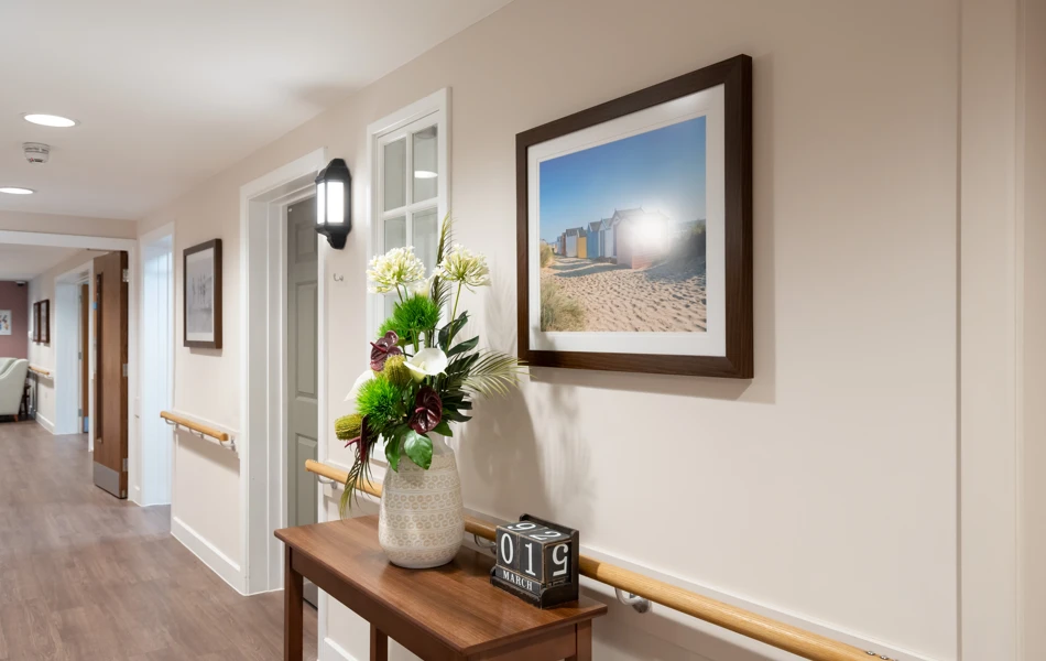 Bright hallway at Westall House with artwork, floral arrangement and handrails