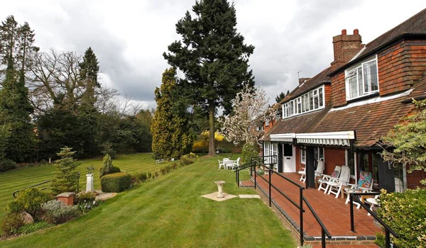 Beautifully landscaped garden with striped lawns and outdoor seating area for residents to enjoy Abbeyfield, Austenmead